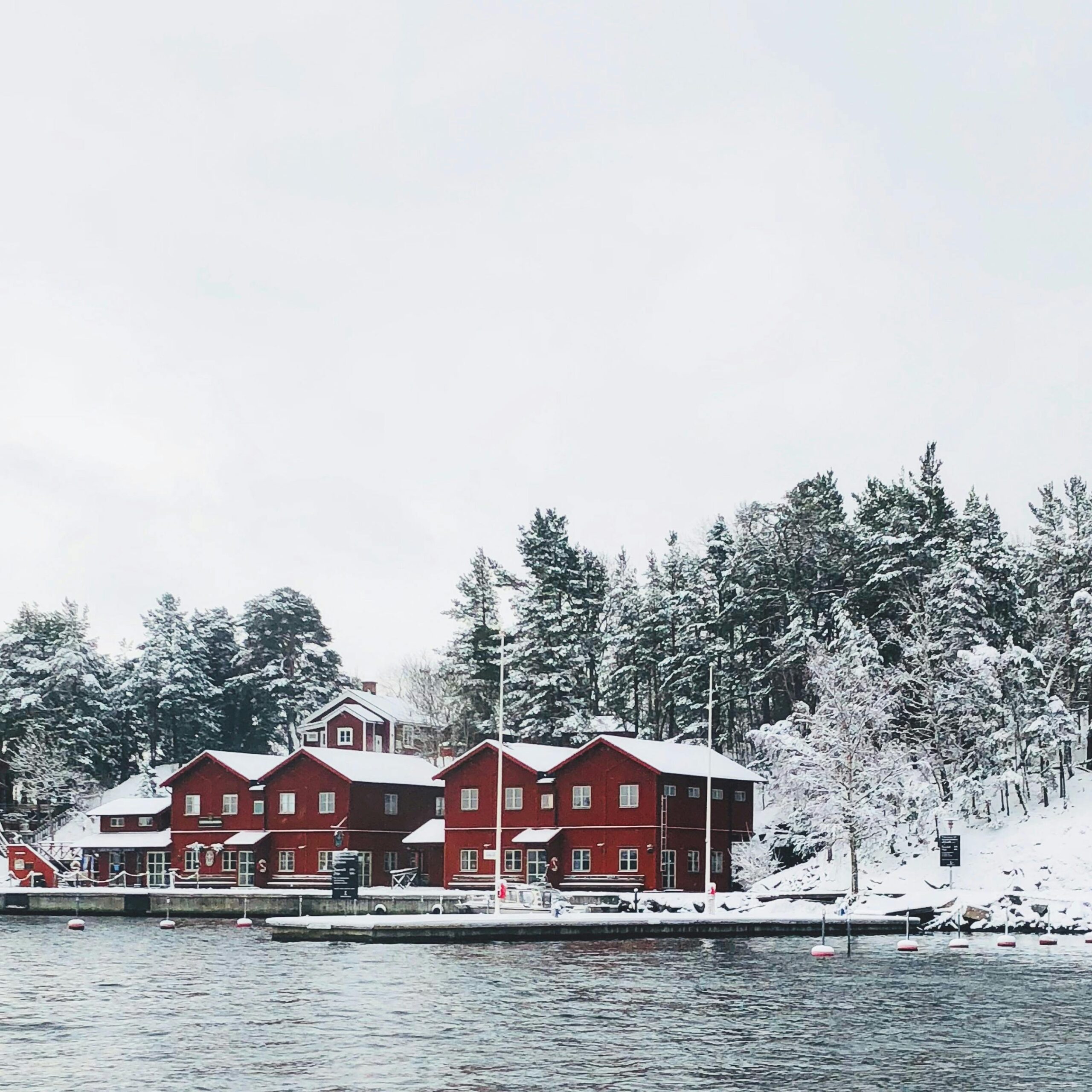 Scenic winter view of red houses by the water in Fjäderholmarna, Sweden.